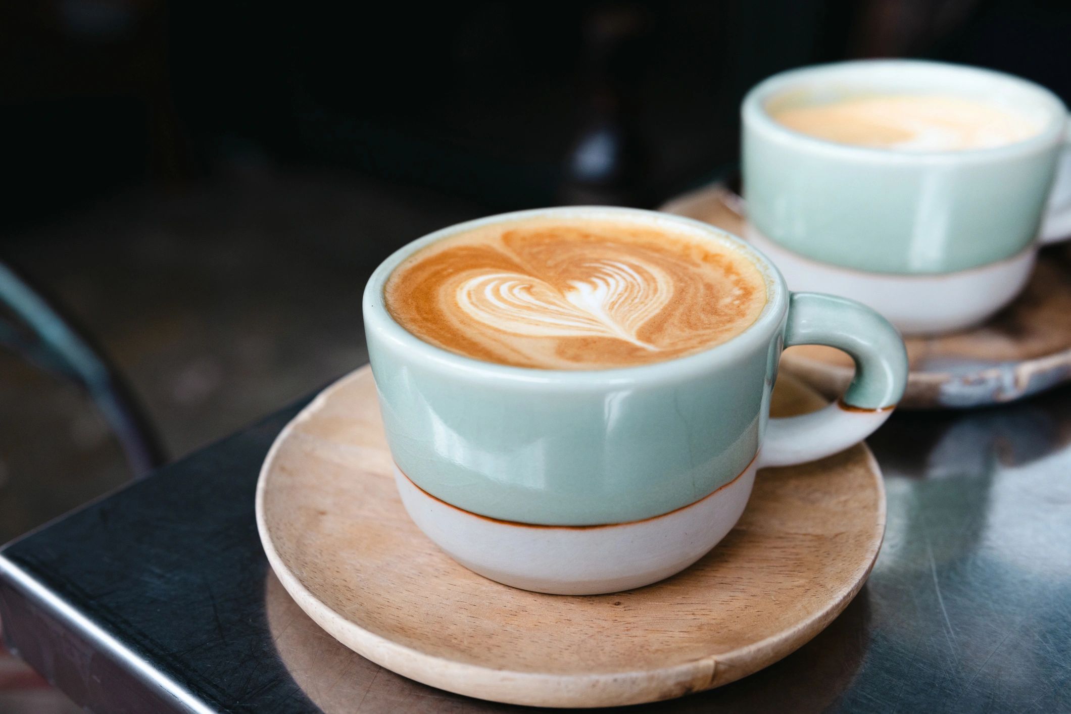 Latte art coffee served in a green mug on a cafe table